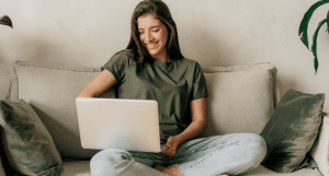 Kvinde der sidder med computer i sofa og tjekker hvilket elselskab hun har